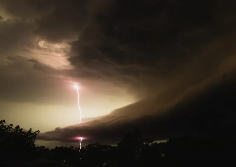 Lightning strikes through dark, stormy clouds at night.